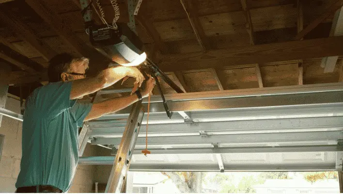 Garage door technician adjusting and aligning safety sensors near the floor