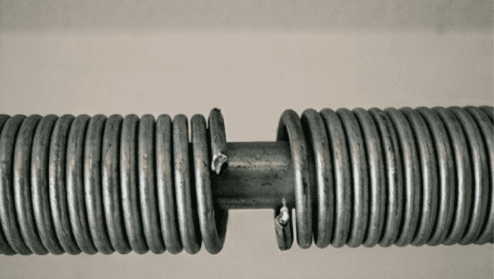 Close up of garage door torsion spring showing visible break and gap in coil
