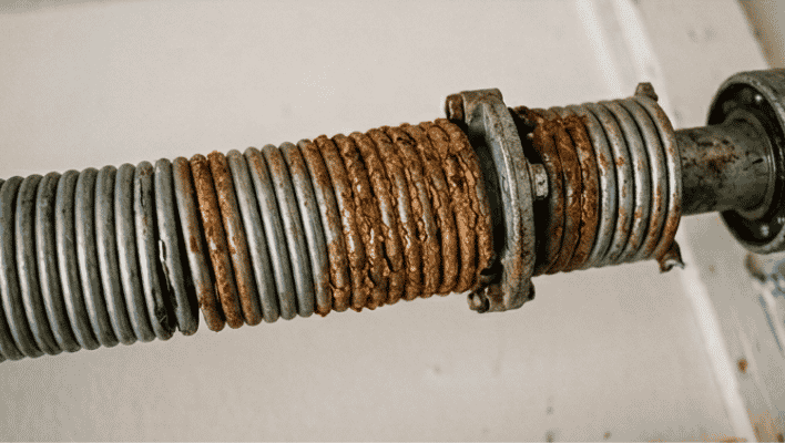 Rust and corrosion on garage door torsion spring causing spring wear and failure
