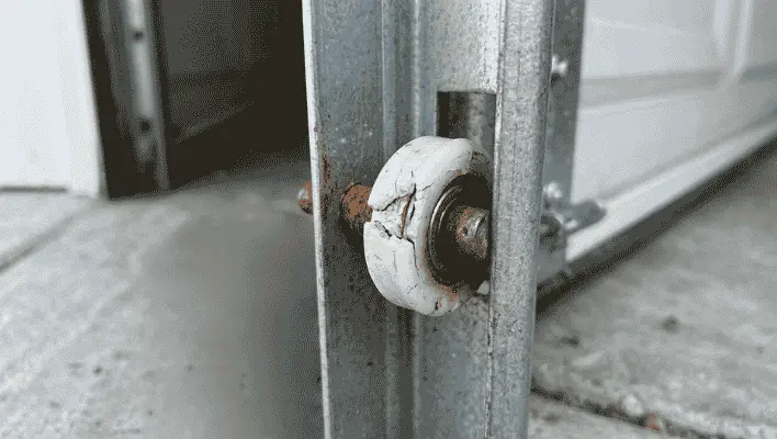 Damaged garage door rollers showing rust and cracks affecting smooth door movement
